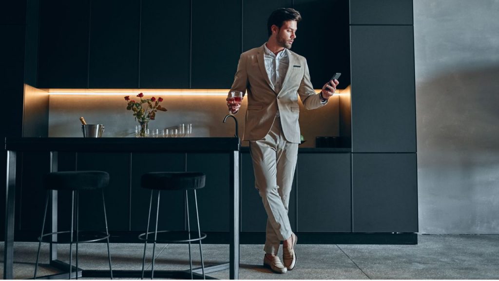 Smart home. Good looking man leaning against modern kitchen bench.